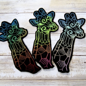 May include: Three black embroidered patches of geometric giraffes with rainbow colored details. The giraffes are facing different directions.
