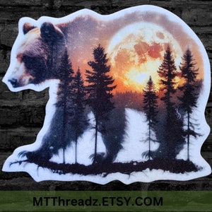 May include: A sticker featuring a bear silhouette with a forest and a full moon in the background. The bear is brown and the trees are black. The moon is orange and yellow. The sticker has a white border and the text "MTThreadz.ETSY.COM" at the bottom.
