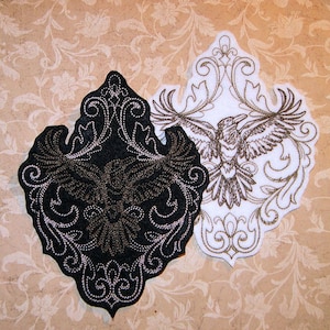 May include: Two embroidered patches featuring a stylized raven with intricate floral designs. One patch is black with gold embroidery, the other is white with gold embroidery.
