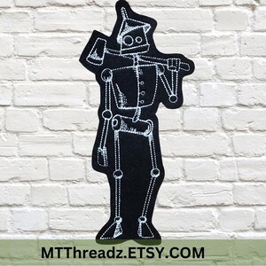 May include: Black iron-on patch featuring a white outline of a robot with a single eye and an axe. The robot is standing with its arms outstretched. The text "MTTThreadz.ETSY.COM" is at the bottom of the patch.