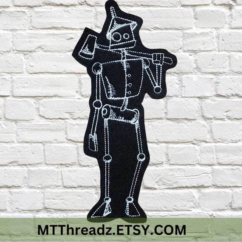 May include: Black iron-on patch featuring a white outline of a robot with a single eye and an axe. The robot is standing with its arms outstretched. The text "MTTThreadz.ETSY.COM" is at the bottom of the patch.