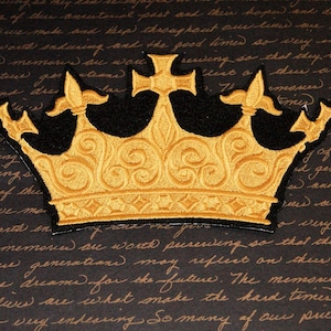 May include: A gold embroidered crown patch with a black background. The crown has a cross on top and intricate details.