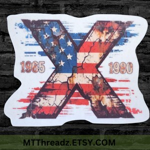 May include: A die-cut sticker featuring a large letter X with a distressed American flag pattern. The design includes the years 1965 and 1980 printed in a weathered font on either side of the X, set against a white background with blue and red.