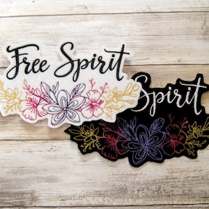 May include: Two embroidered patches with the text "Free Spirit" and floral designs. The top patch is white with black text and colorful flowers. The bottom patch is black with white text and purple flowers.