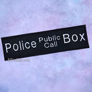 May include: Black and white sign with the text "Police Public Call Box".