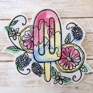 May include: Embroidered patch featuring a colorful popsicle with a yellow stick, surrounded by black line drawings of flowers, berries, and leaves.