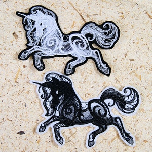 May include: Two embroidered iron-on patches of unicorns, one black and one white. Both unicorns are in a delicate lace design.