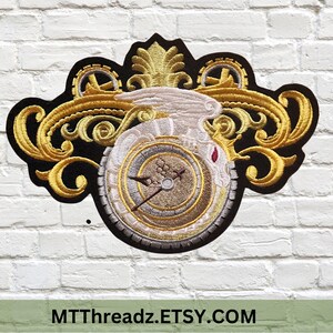 May include: A gold and white embroidered patch featuring a clock face with a white bird and ornate gold scrollwork. The patch is on a black background.