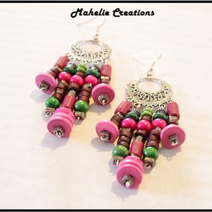 May include: A pair of dangle earrings with silver filigree and pink, green, and brown wooden beads.