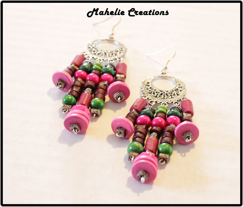 May include: A pair of dangle earrings with silver filigree and pink, green, and brown wooden beads.