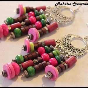 May include: A pair of dangle earrings with a silver filigree design and colorful wooden beads. The beads are pink, green, and brown. The earrings are approximately 3 inches long.