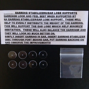May include: Eight clear plastic earring stabilizers or ear lobe supports in a clear plastic bag. The stabilizers are small, round discs with a hole in the center. The bag is sealed with a zipper. The text on the white paper reads: "EARRING STABILIZERS/EAR LOBE SUPPORTS EARRINGS LOOK AND FEEL BEST WHEN SUPPORTED BY AN EARRING STABILIZER/EAR LOBE SUPPORT. THESE WILL HELP TO EVENLY DISTRIBUTE THE WEIGHT OF THE EARRING. THIS WILL SUPPORT THE EAR LOBE WHICH HELP MINIMIZE IRRITATION. THESE WILL ALSO BALANCE THE EARRINGS AND THEY WILL LOOK SO MUCH BETTER ON. SIMPLY INSERT EARRING IN EAR, INSERT EARRING STABILIZER DISC THROUGH POST BEHIND EAR, PUT EARRING BACKING ON AND OBSERVE THE IMPROVEMENT!!!"