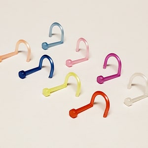 May include: A set of ten colorful plastic nose rings. The rings are in various colors, including blue, pink, yellow, and orange. The rings are all the same size and shape.