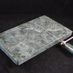 May include: Green marble cheese board with a built-in wire cheese slicer. The board has a green marble handle.