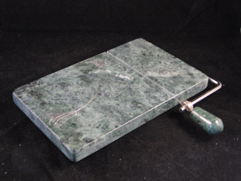 May include: Green marble cheese board with a built-in wire cheese slicer. The board has a green marble handle.