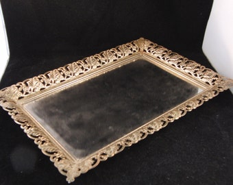 May include: A silver-toned rectangular tray with a mirrored surface and an ornate, leaf-shaped border.