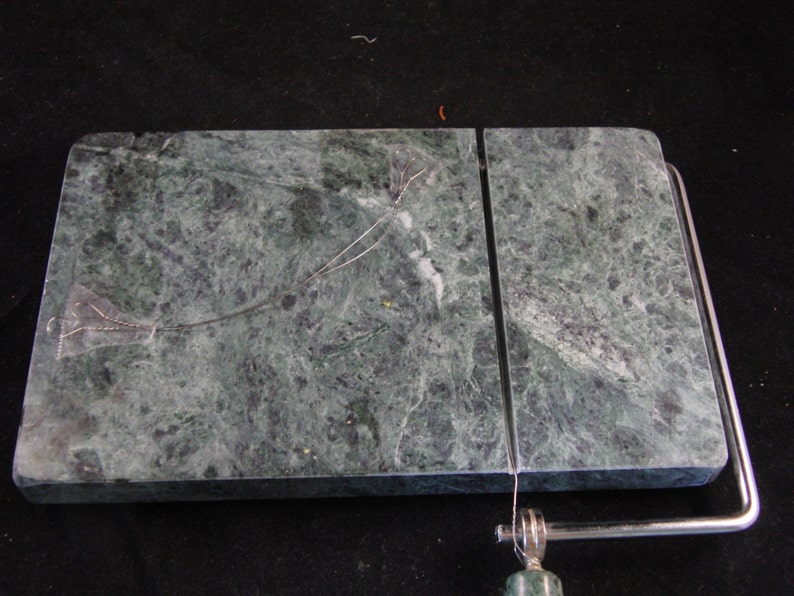 May include: A green marble cheese board with a built-in wire cheese cutter. The board is divided into two sections.