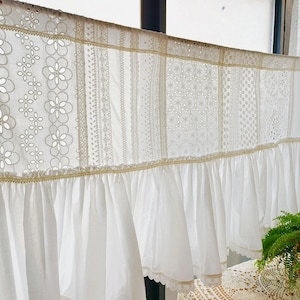 May include: White lace valance with a ruffled bottom edge. The valance is made of several different lace panels sewn together.