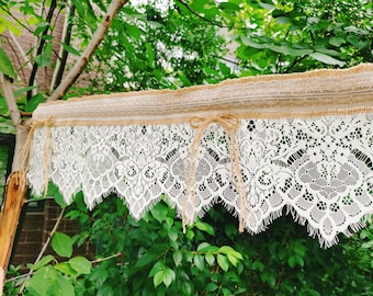 May include: A white lace trim with a burlap ribbon sewn on top. The lace trim has a scalloped edge and a delicate floral pattern.