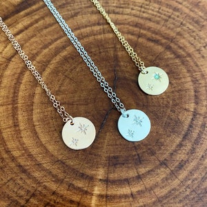 May include: Three delicate necklaces with starburst pendants. The pendants are silver, gold, and gold with a green gemstone.