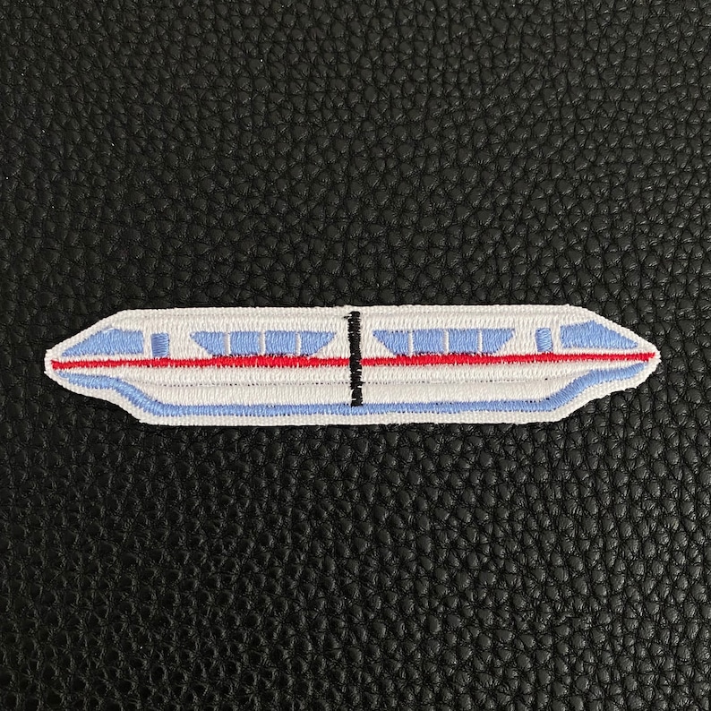 May include: A white and blue embroidered patch of a monorail train with red accents.