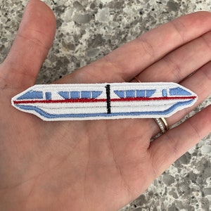 May include: White embroidered patch of a monorail train with red and blue details.