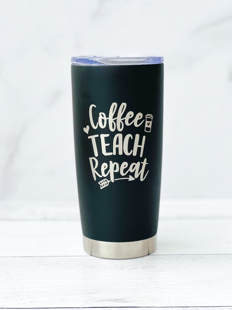 K&ouml;nnte beinhalten: Ein schwarzer Edelstahlbecher mit einer wei&szlig;en Aufschrift "Coffee Teach Repeat" mit einem kleinen Kaffeetassen-Symbol und einem Pfeil.