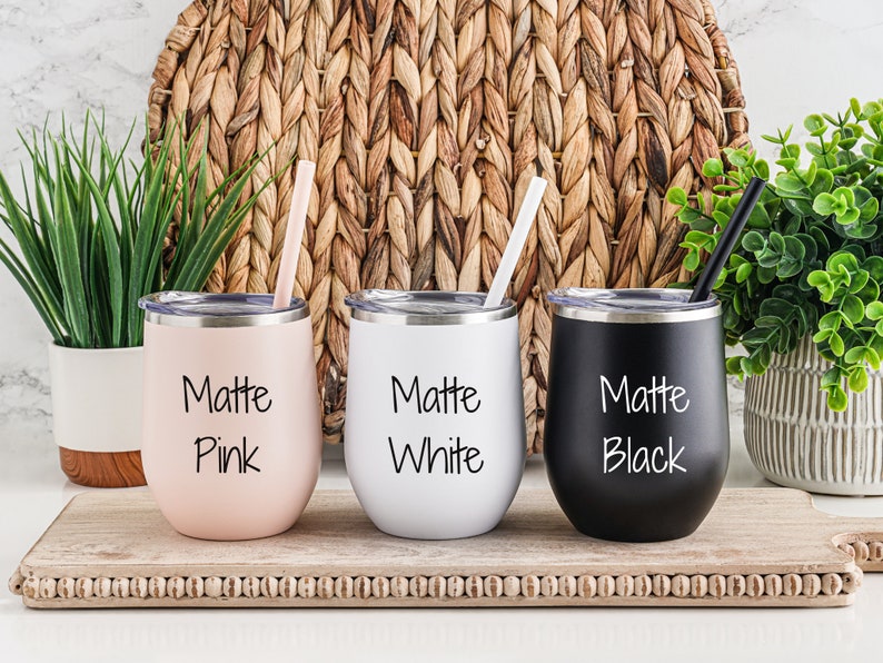 K&ouml;nnte beinhalten: Drei Edelstahlbecher mit Deckel und Strohhalmen. Die Becher sind mattrosa, wei&szlig; und schwarz. Jeder Becher tr&auml;gt die Aufschrift "Matte" und die Farbe des Bechers.