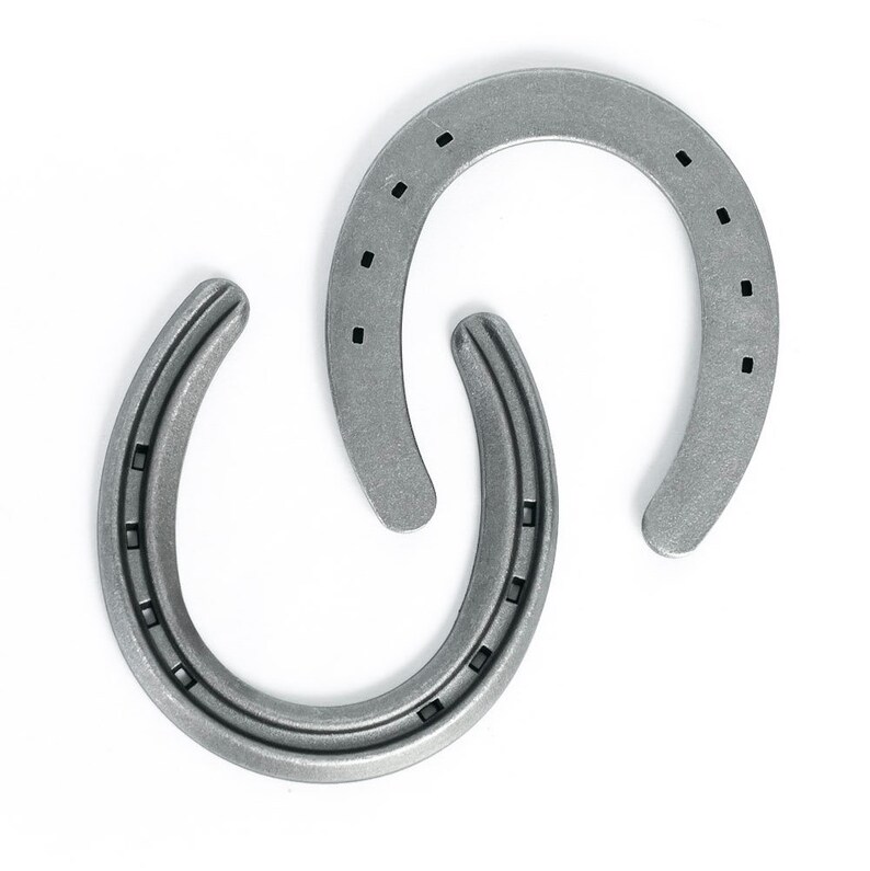 May include: Two silver-colored horseshoes arranged in a decorative pattern against a white background. Each horseshoe has a U-shape with multiple nail holes. The metal has a slightly textured appearance.