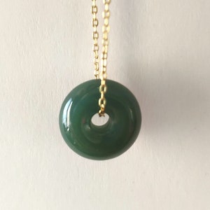 May include: A gold chain necklace with a green jade donut pendant.