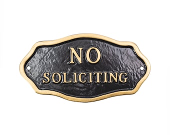 May include: Black metal sign with a gold border that reads "NO SOLICITING".