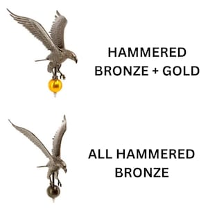 May include: Two eagle finials with wings spread. The top eagle is hammered bronze with a gold sphere base, labeled HAMMERED BRONZE + GOLD. The bottom eagle is entirely hammered bronze, labeled ALL HAMMERED BRONZE. Both feature detailed feathers.