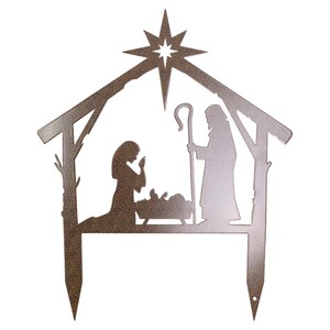 Puede incluir: Una silueta de metal de la escena de la natividad con una estrella en la parte superior. Las figuras son Mar&iacute;a, Jos&eacute; y el ni&ntilde;o Jes&uacute;s en un pesebre. La silueta es marr&oacute;n y est&aacute; dise&ntilde;ada para colocarse en el suelo.