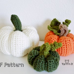 May include: Three crocheted pumpkins in white, orange, and green. The pumpkins are all different sizes and have a textured surface. The text "PDF Pattern" and "Yarrrn It" is visible in the image.