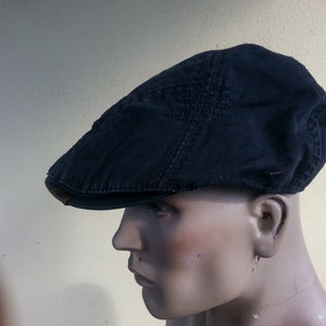 Puede incluir: Gorra plana azul marino oscuro con visera marrón. La gorra está hecha de una tela texturizada y tiene un diseño clásico y atemporal. Este sombrero es un accesorio elegante para cualquier atuendo casual.