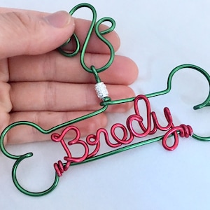 May include: Green wire dog bone ornament with a red wire name "Brady" and a silver bead.