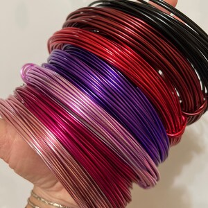 May include: A stack of colorful aluminum wire in various shades of red, purple, and pink. The wire is coiled and ready for crafting projects.