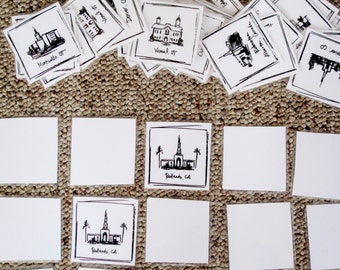 May include: A set of 12 blank white square cards with black ink drawings of various churches and temples. The cards are arranged in a grid pattern on a brown carpet. The text on the cards includes the names of the locations, such as "Redlands, CA", "Vemal, UT", and "Martiallo, OT".