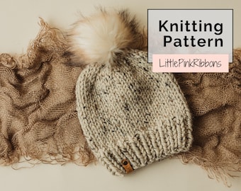 May include: A chunky knit beanie in a speckled oatmeal colour with a large faux fur pom-pom on top and a small brown leather tag at the brim. The image includes the text Knitting Pattern and LittlePinkRibbons in a rectangular overlay.