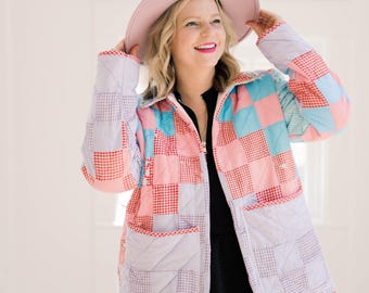 May include: A patchwork jacket in pastel colors, featuring squares of pink, blue, and red gingham and solid fabrics. The jacket has a zipper closure and two front pockets. A matching pink hat is also visible.