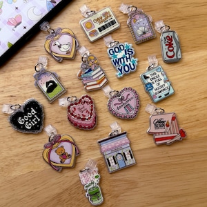 May include: A collection of colorful acrylic charms with various designs, including a duck, a bear, a book, a soda can, and text that reads "Good Girl", "God is with You", and "Pretty Girls matcha".