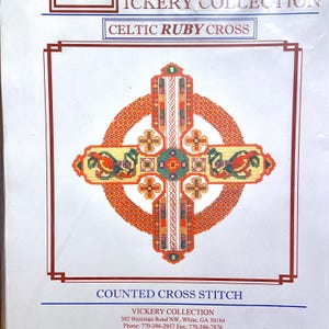 May include: A counted cross stitch pattern featuring a Celtic Ruby Cross. The cross is red, green, yellow, and white. The pattern is from the Vickery Collection.
