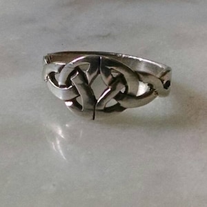Könnte beinhalten: Ein silberner Ring mit einem detaillierten keltischen Knoten.