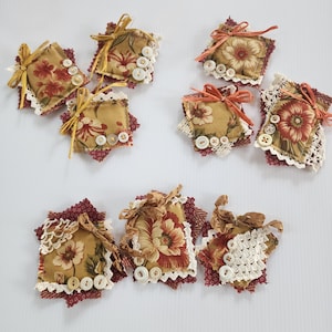 May include: Assortment of handmade fabric sachets with floral patterns and lace trim. The sachets are filled with dried herbs and flowers, and are perfect for adding a touch of fragrance to any room.