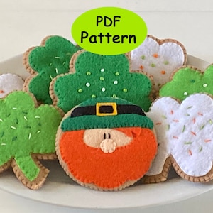 May include: A PDF pattern for felt shamrock cookies and a leprechaun face. The cookies are decorated with green, white, and orange felt and have sprinkles.