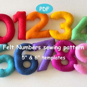 Può includere: Una collezione di numeri in feltro colorati, da 0 a 9, in varie tonalità vivaci. I numeri sono disposti su una superficie bianca. Il testo sull'immagine recita "Felt Numbers sewing pattern 5" & 6" templates".