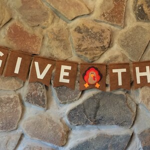 May include: A brown felt banner with white letters spelling "GIVE THANKS" and a brown felt turkey in the middle.