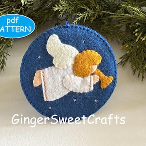 May include: A circular blue felt ornament featuring a white angel with gold hair playing a gold trumpet. The angel is surrounded by small white embroidered stars. The text pdf PATTERN and GingerSweetCrafts are visible on the image.