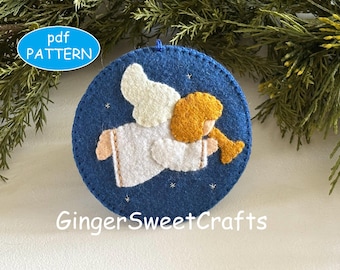 May include: A circular blue felt ornament featuring a white angel with gold hair playing a gold trumpet. The angel is surrounded by small white embroidered stars. The text pdf PATTERN and GingerSweetCrafts are visible on the image.