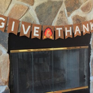 May include: A brown felt banner with white letters that reads "GIVE THANKS" with a brown felt turkey in the middle.